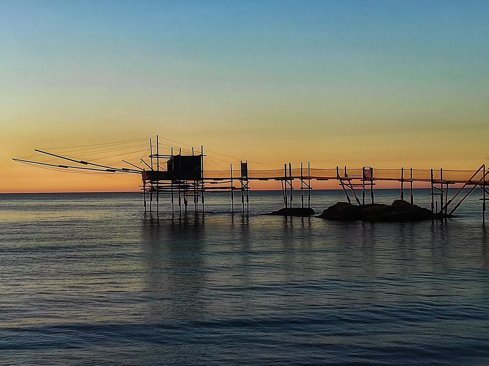 Un trabocco al tramonto, con antenne e reti calate in mare